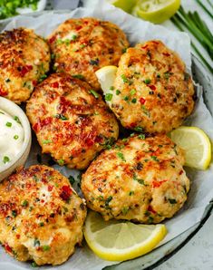 crab cakes with lemon wedges and sour cream on a white plate next to garnishes