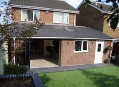 a brick house with an open garage door in the front yard and grass on the ground