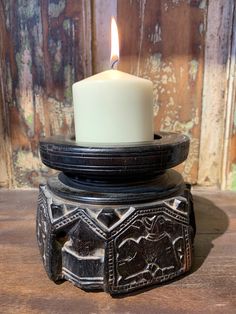 a candle holder with a lit candle on top of it sitting on a wooden table