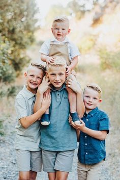 three young boys are posing for the camera while one boy is on top of them