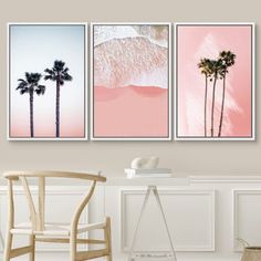 three palm trees in front of a pink wall with watercolor paint on it and the ocean behind them