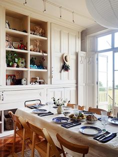 a dining room table is set with plates and place settings in front of a large window