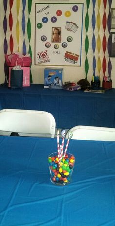 there is a candy bowl on the blue table cloth in front of the wall with pictures