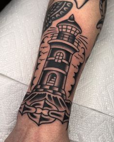 a black and white lighthouse tattoo on the arm