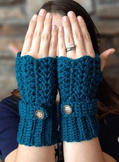 a woman is holding her hands up to her face while wearing knitted fingerless gloves