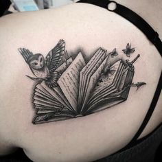 an open book tattoo on the back of a woman's upper arm and shoulder