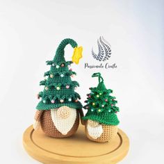 two small crocheted christmas trees sitting on top of a wooden stand next to each other