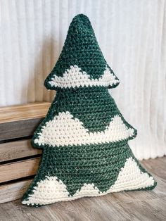 a crocheted green and white christmas tree sitting on top of a wooden bench