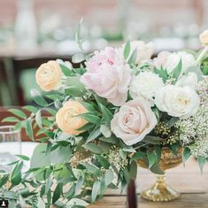 a vase filled with flowers sitting on top of a wooden table covered in greenery