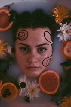 a woman is surrounded by oranges and flowers