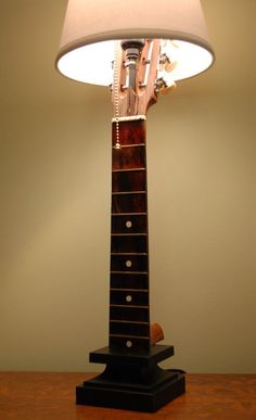 a lamp that is sitting on top of a wooden table next to a guitar case