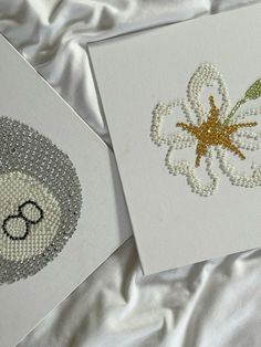 two cards with bead designs on them sitting next to each other in white sheets