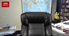 a black recliner chair sitting in front of a bed with a world map on the wall