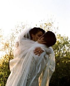 a bride and groom kissing in front of trees