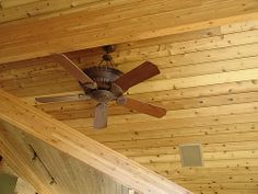 a ceiling fan mounted on the side of a wooden wall