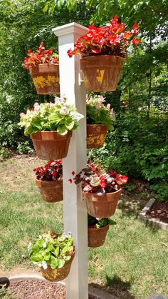 a white pole with potted plants hanging from it's sides in a garden