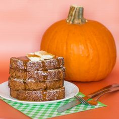 a stack of french toast sitting on top of a white plate next to a pumpkin