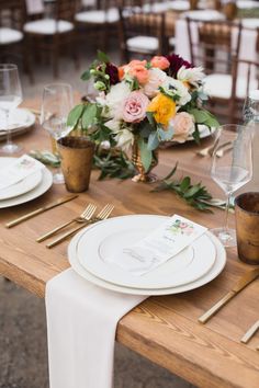 the table is set with white plates and gold cutlery, silverware, and flowers