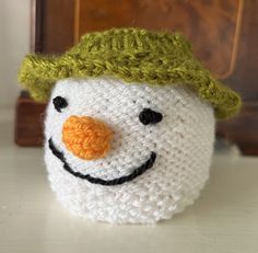 a crocheted snowman with a green hat on it's head and nose