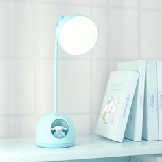 a blue lamp sitting on top of a white table next to books and a mirror