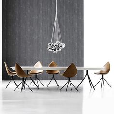 a modern dining table with six chairs and a chandelier hanging from the ceiling