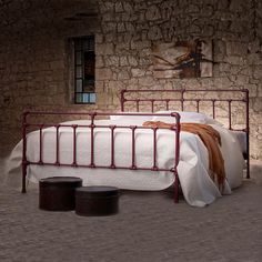 a bed sitting in the middle of a room next to a stone wall with a painting on it