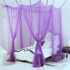 a white bed with purple curtains on top of it