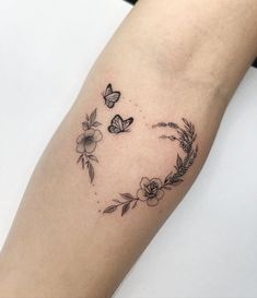 a woman's arm with flowers and butterflies in the shape of a heart on it