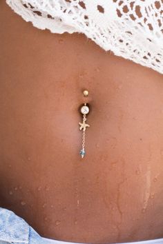 a woman's belly is adorned with a gold cross and turquoise stone bead necklace