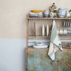 an old wooden shelf with dishes and plates on it next to a wall mounted rack