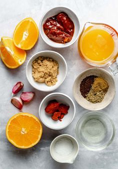 oranges, spices, and other ingredients are arranged in bowls on a white surface