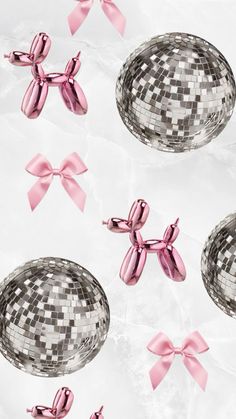 pink bows and silver disco balls on a white surface with one shiny ball in the middle