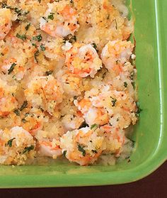 a green casserole dish filled with shrimp and cheese