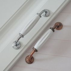 two white handles on the side of a door with knobs and pulls attached to it