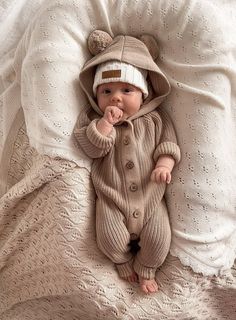 a baby in a bear suit laying on a bed