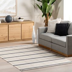 a living room with a gray couch and white rug on the floor next to a wooden cabinet