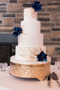 a white and gold wedding cake with blue flowers