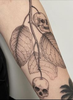 a skull and leaves tattoo on the arm