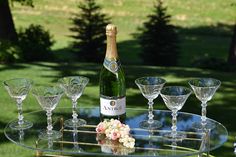 a table with wine glasses and a bottle on it in front of a grassy area