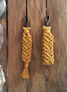 two yellow rope keychains hanging from hooks on a wooden table with other items