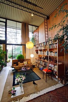 a living room filled with lots of furniture next to a tall book shelf full of books