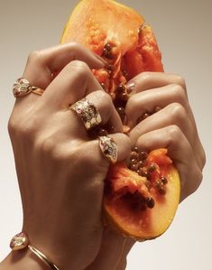 a woman holding a piece of fruit up to her face with two rings on it