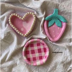 three pink and white plates sitting on top of a bed