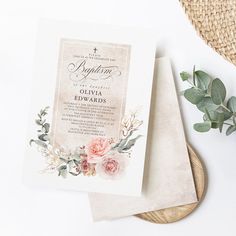 two wedding cards with flowers on them next to a straw hat and some greenery