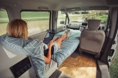 a woman sitting in the back of a van using a tablet