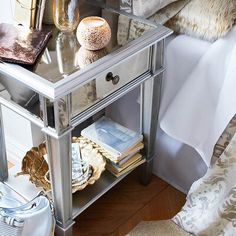 a mirrored nightstand with books and glasses on it