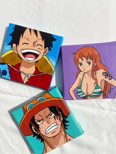 three anime characters painted on wooden coasters sitting on a white sheet in front of a bed