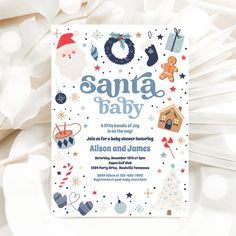 a christmas baby shower with santa and other holiday items on the front, in white paper