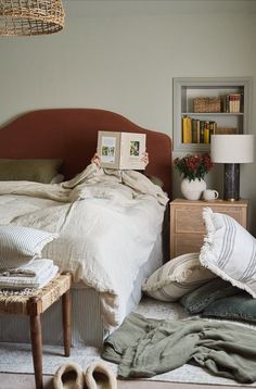 an unmade bed with pillows and blankets on the floor next to a book shelf