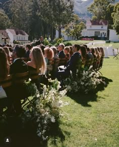 a group of people sitting in chairs on top of a lush green field